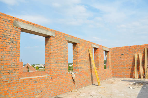 Unfinished brick house construction with windows, concrete lintels and no roof.